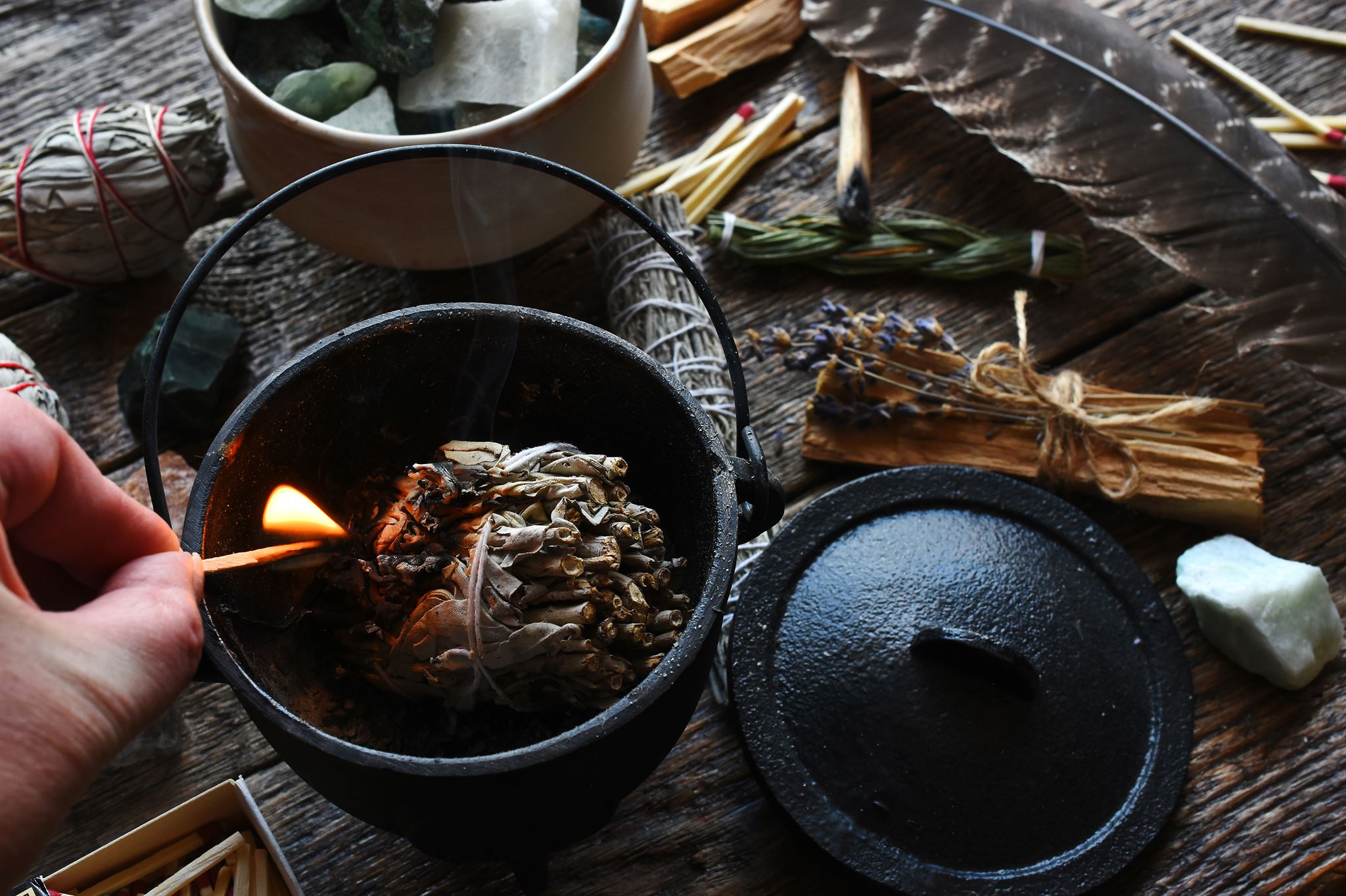 Hand-lighting-sage-bundle-in-iron-pot